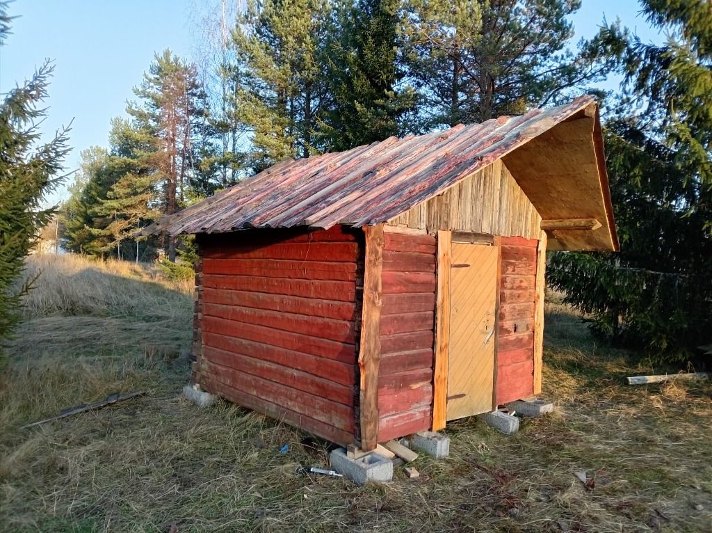 Vanhoista punaisista hirsistä koottu ulkorakennus